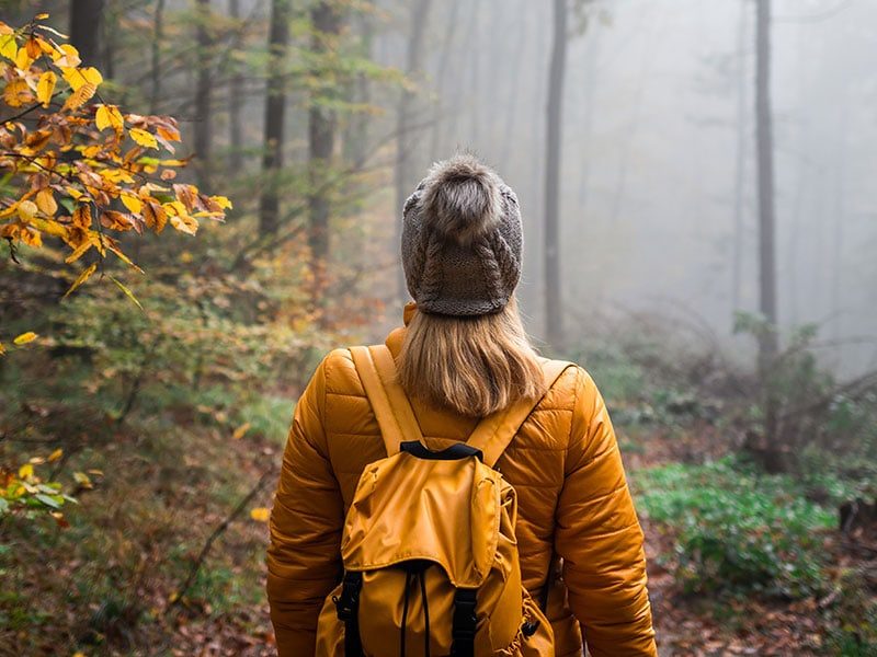 Hiker with backpack walking through foggy forest in New River Gorge.