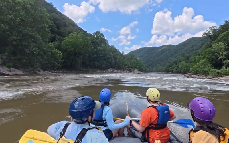 Group of rafters navigating the rapids in New River Gorge.