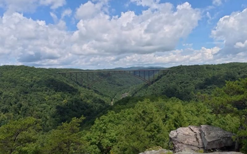Scenic view of New River Gorge Bridge and lush green landscape.