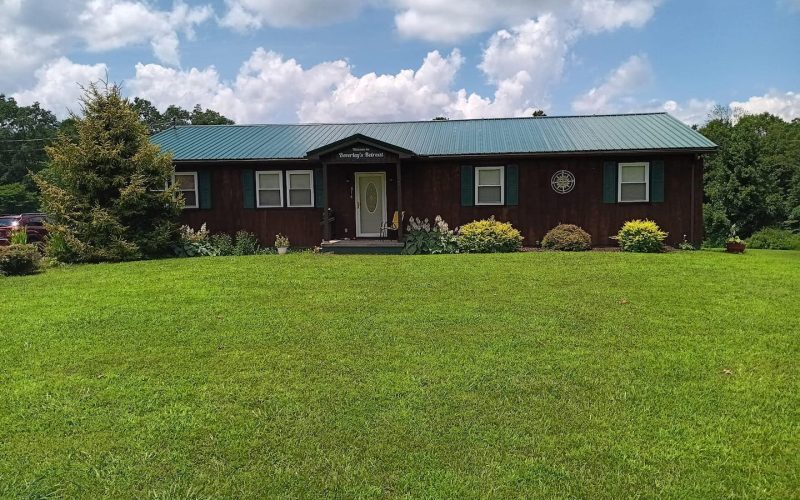 Cozy house at New River Gorge with lush lawn and trees.