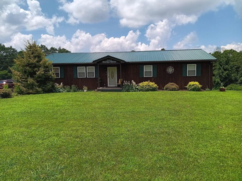 Cozy house at New River Gorge with lush lawn and trees.